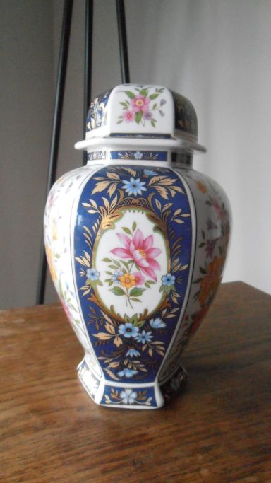 Blauwe en witte vaas met bloemenmotieven en een decoratief deksel.