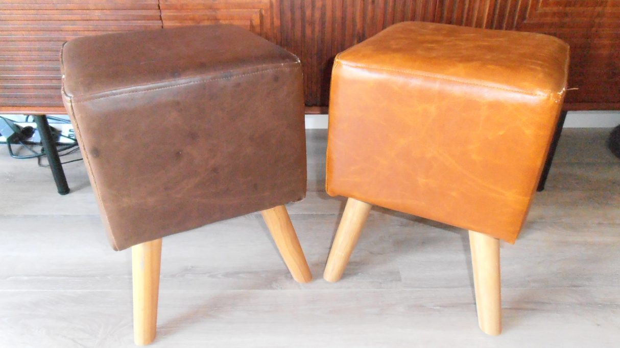 Twee vintage krukken met houten poten, één bruin en één oranje.