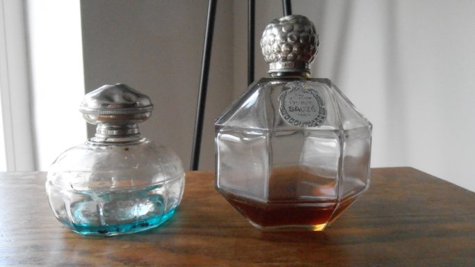 Twee vintage parfumflessen, één met een blauwe vloeistof en één met een bruine vloeistof.